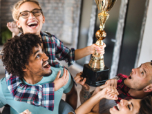 Foto von jubelnden jungen Menschen, die einen Sportpokal in die Höhe halten. 